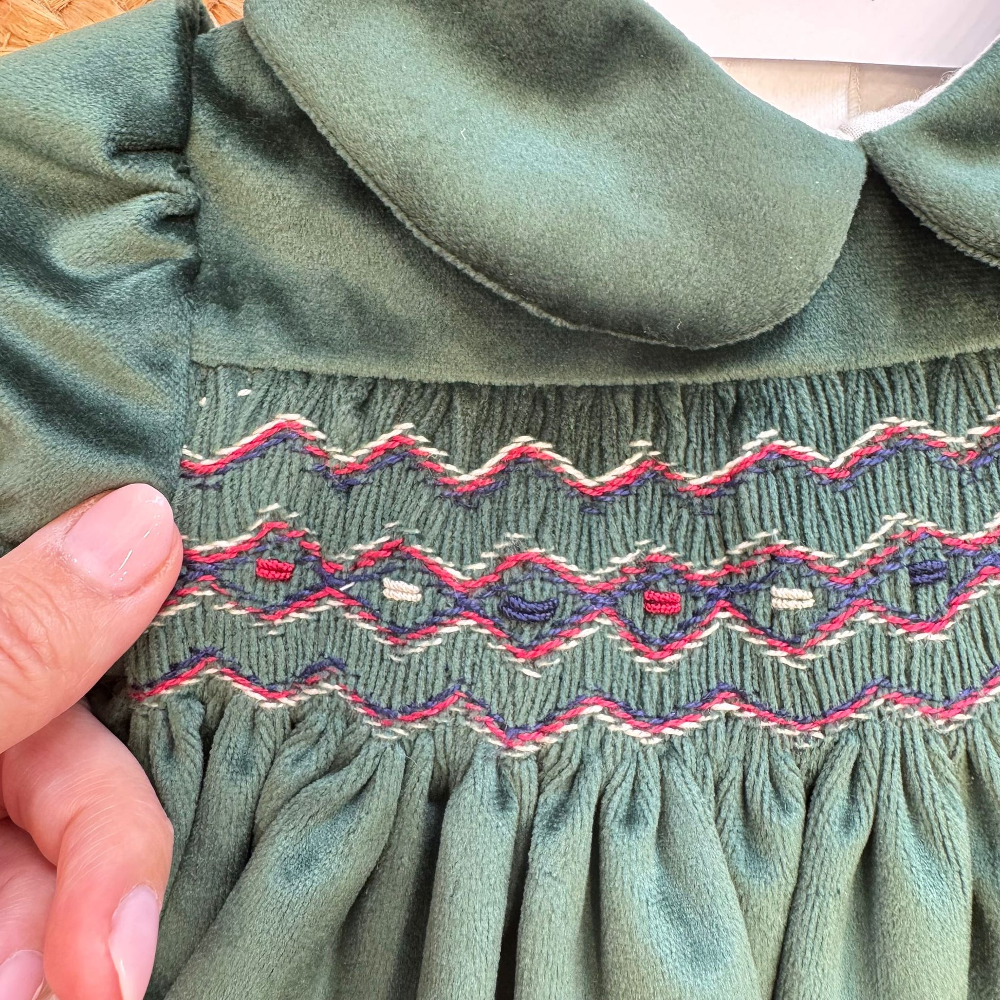 ricamo a nido d’ape rosso e blu su abito natalizio neonata