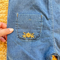 Salopette bimba in 100% cotone denim blu con tasche e ricami floreali beige