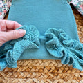 Completo bimba con salopette in maglia verde petrolio e camicia floreale a maniche lunghe