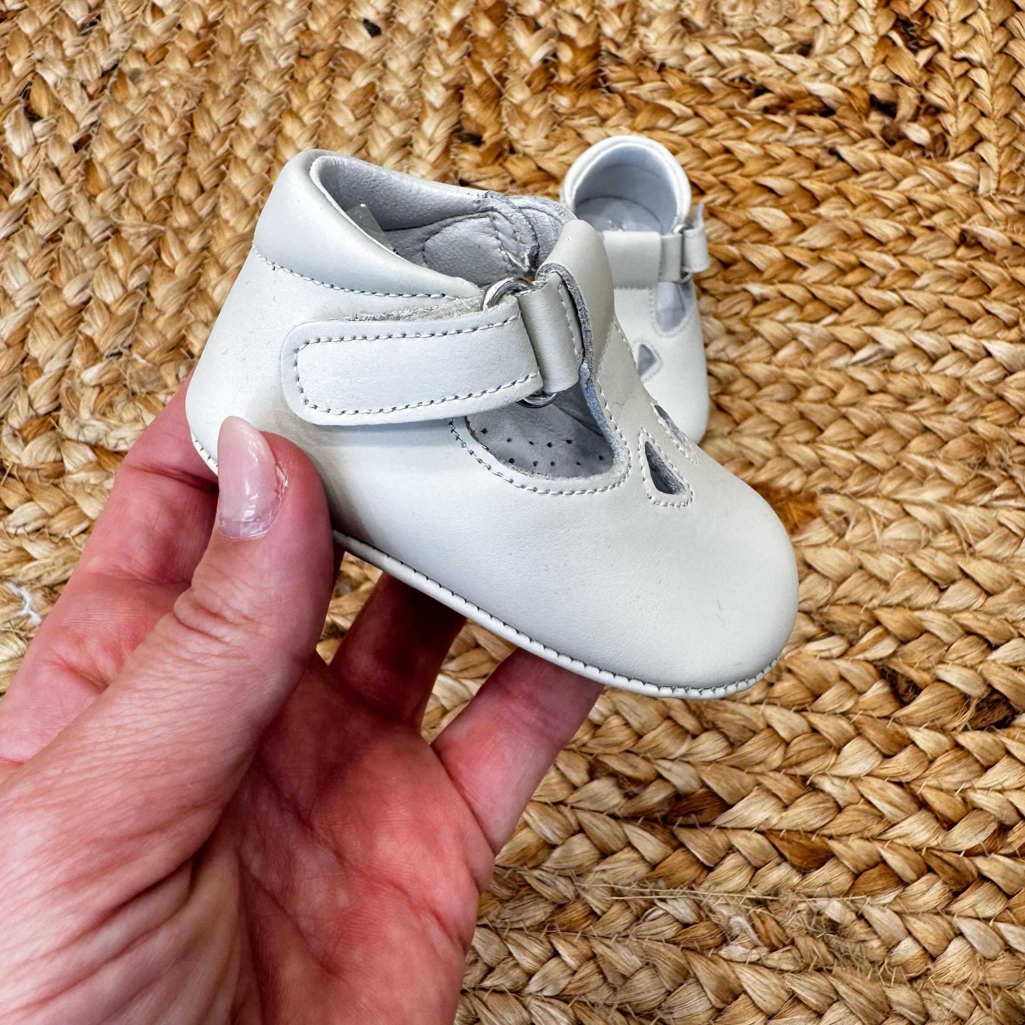Scarpa morbida per neonati in pelle bianca con chiusura a cinturino e design raffinato