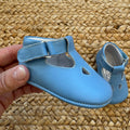 Scarpe battesimo bimbo azzurro con cinturino e dettagli decorativi frontali.