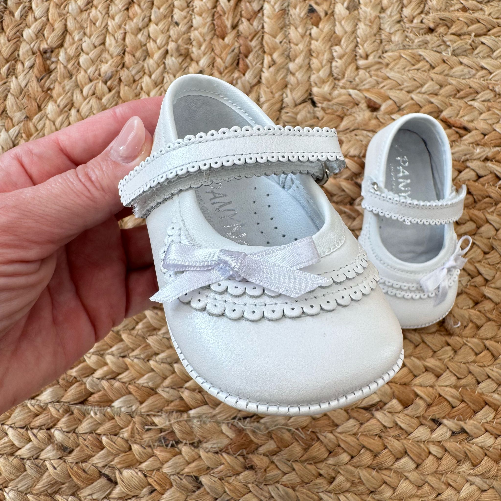 Scarpe culla bianche con trafori, cinturino e fiocco in raso
