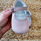 Scarpa culla rosa tenuta in mano per mostrare la morbidezza e i dettagli del materiale.