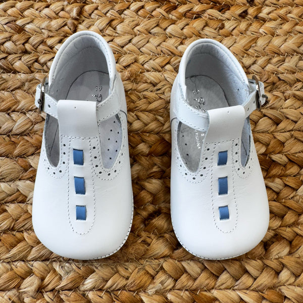 Scarpa culla in pelle bianca con dettagli azzurri e fibbia, ideale per battesimi e cerimonie.