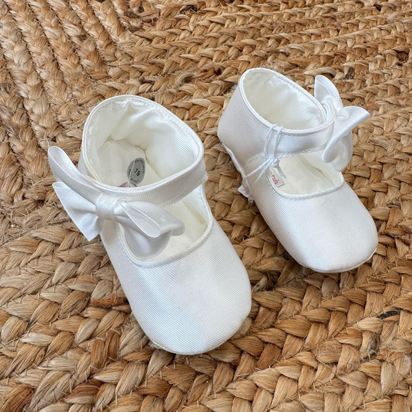 Scarpa culla in raso avorio con fiocco laterale, vista dall’alto.