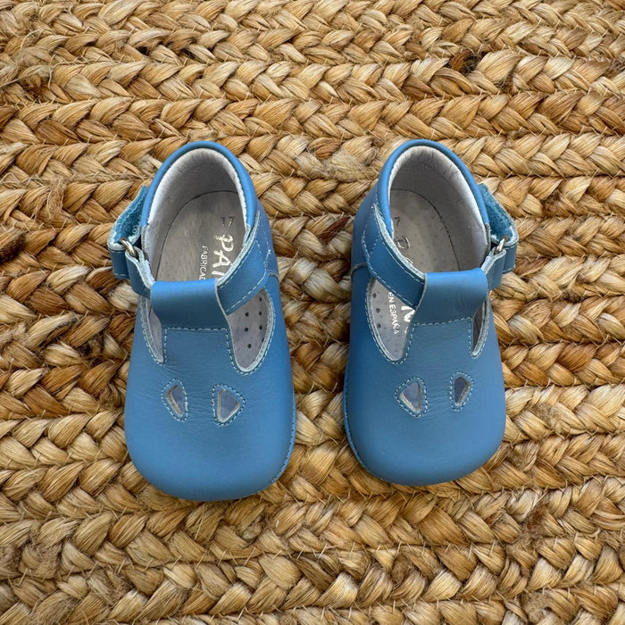 Scarpe battesimo bimbo azzurro con cinturino e dettagli decorativi frontali.