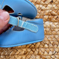 Scarpe battesimo bimbo azzurro con cinturino e dettagli decorativi frontali.