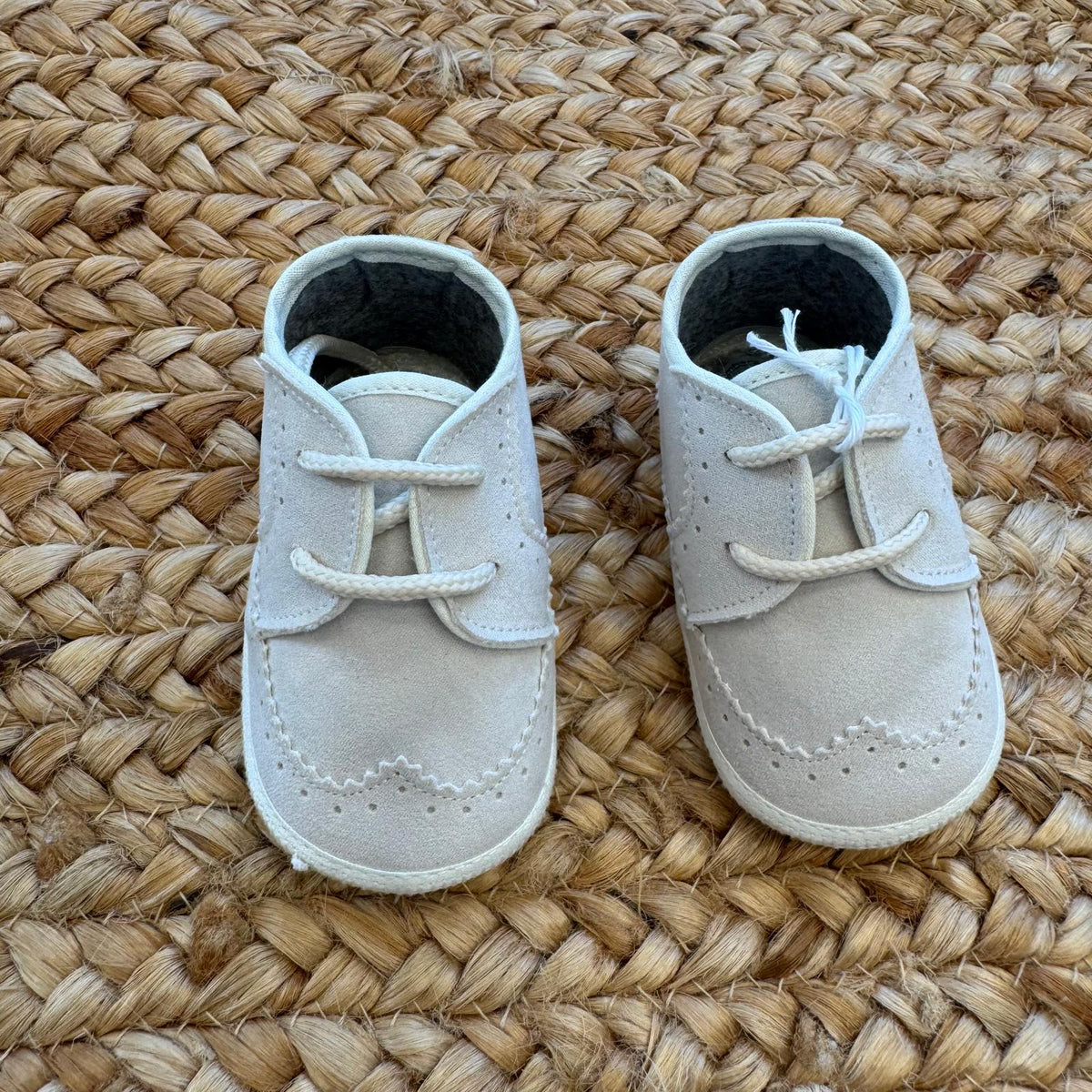 Dettaglio scarpa elegante bimbo beige con lacci, cuciture e lavorazione traforata