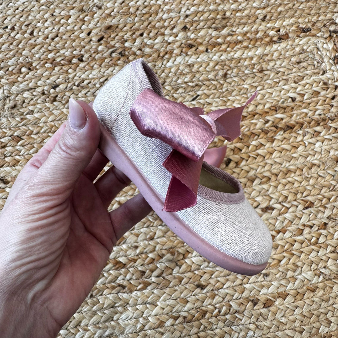 Scarpe culla modello ballerina in tessuto rosa con fiocco in raso coordinato, ideali per cerimonie e occasioni speciali.