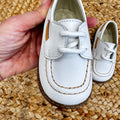 Primo piano delle scarpe culla modello barchetta con lacci e rifiniture beige, per un look classico e raffinato.