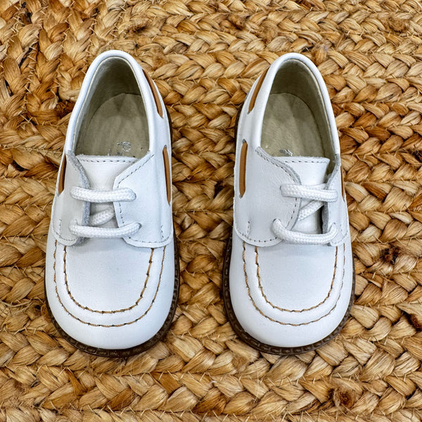 Scarpe culla modello barchetta in pelle bianca con cuciture a contrasto e chiusura a lacci, ideali per neonati in occasioni speciali.

