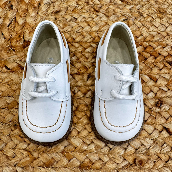 Scarpe culla modello barchetta in pelle bianca con cuciture a contrasto e chiusura a lacci, ideali per neonati in occasioni speciali.

