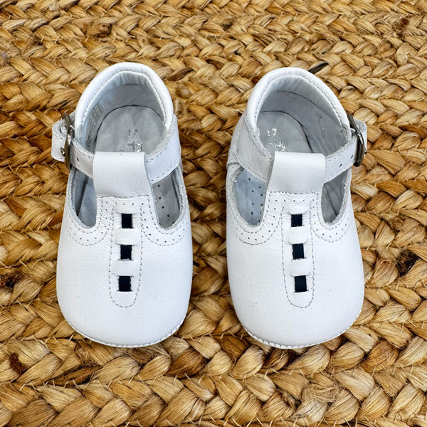 Scarpe culla bianche in pelle con design T-bar e chiusura laterale con fibbia, ideali per battesimo e cerimonia.
