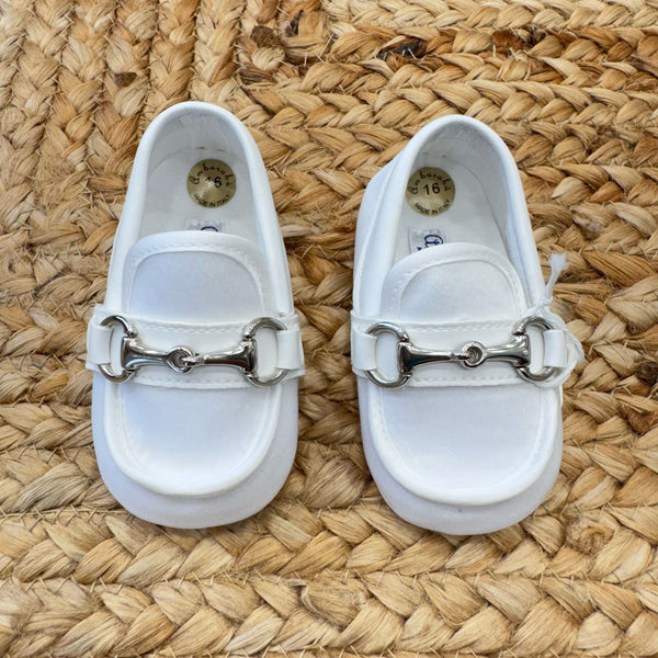 Scarpe culla stile mocassino in raso bianco con dettaglio metallico frontale, ideali per battesimo e cerimonia.