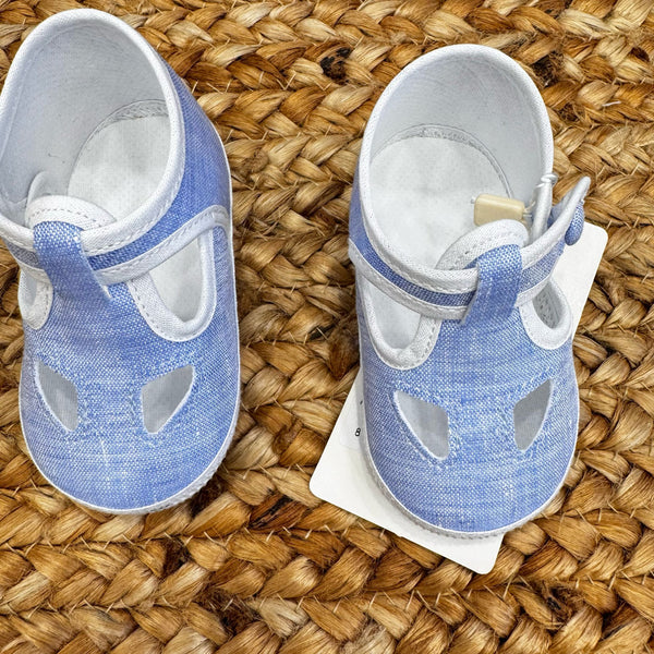 Scarpe culla in tessuto azzurro con dettagli traforati e chiusura con cinturino regolabile, ideali per neonati in primavera ed estate.