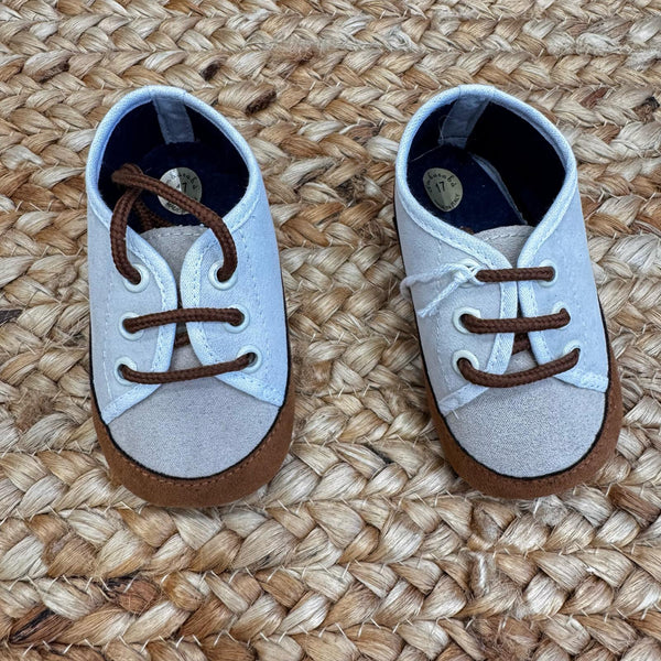 Scarpe culla in tessuto bicolore beige e bianco con punta rinforzata in suede marrone e chiusura a lacci. Perfette per neonati.