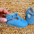 Scarpe battesimo bimbo azzurro con cinturino e dettagli decorativi frontali.