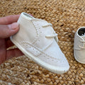 Dettaglio scarpa elegante bimbo beige con lacci, cuciture e lavorazione traforata