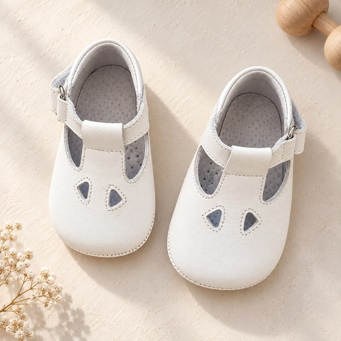 Scarpe battesimo bimbo bianche con cinturino e dettagli frontali decorativi.