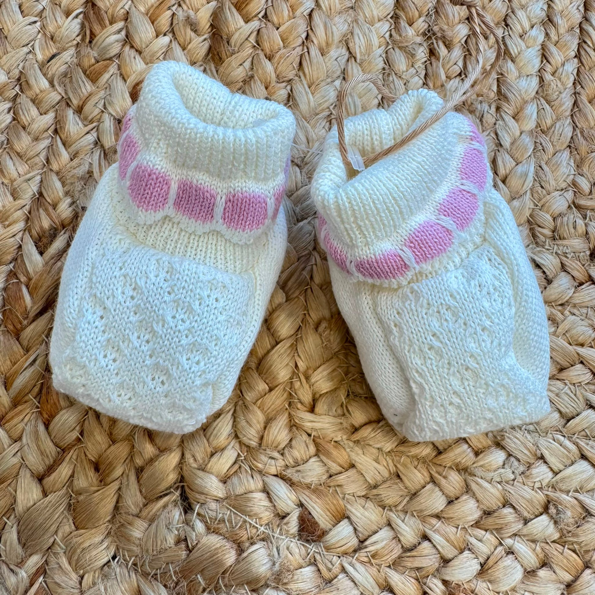 Dettaglio colletto e lavorazione traforata della tutina neonata panna e rosa in lana
