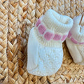 Dettaglio colletto e lavorazione traforata della tutina neonata panna e rosa in lana