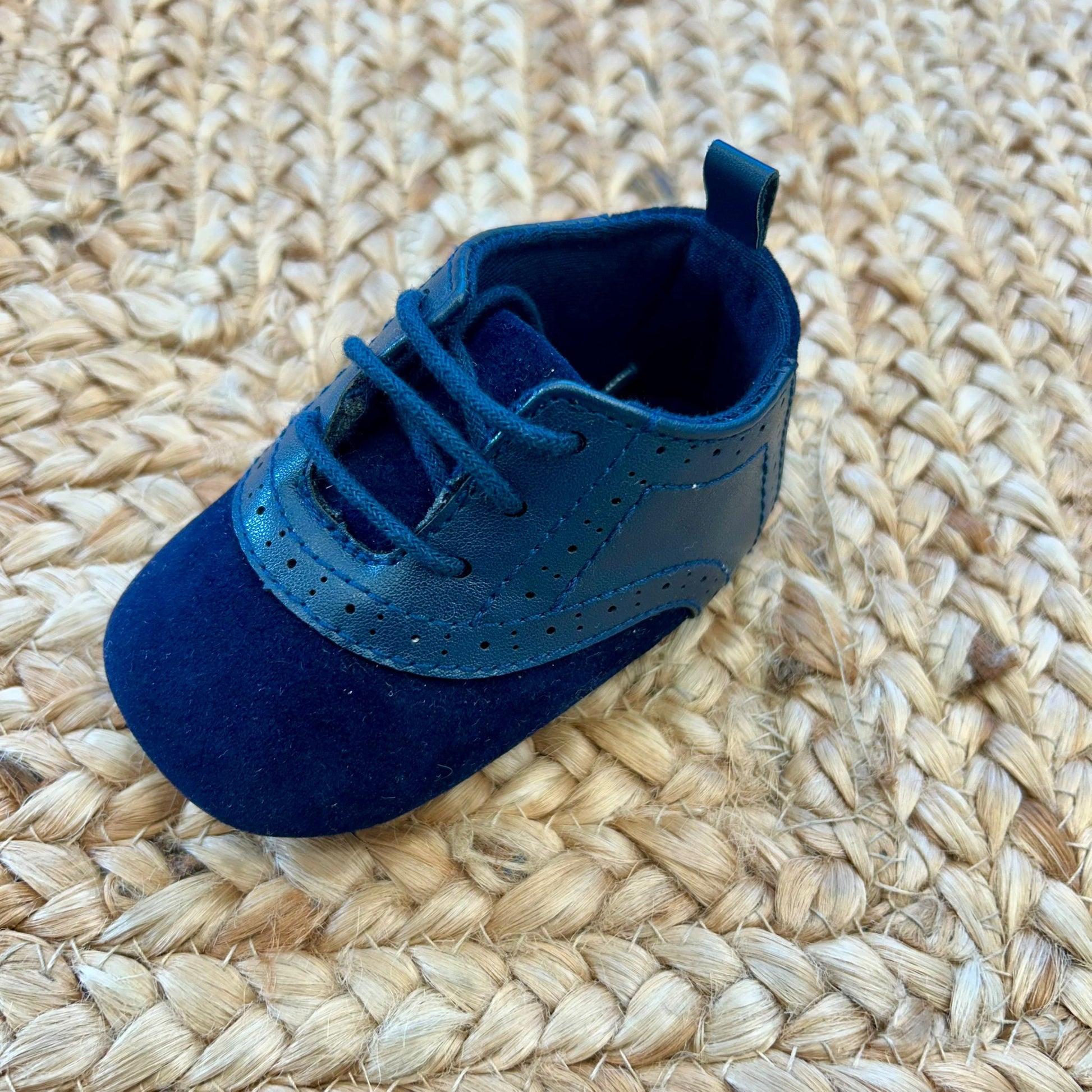 “scarpina battesimo bimbo blu con dettagli traforati vista laterale”