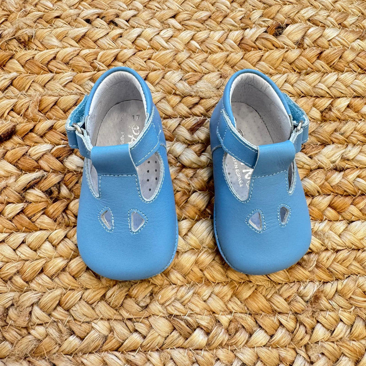 Scarpe battesimo bimbo azzurro con cinturino e dettagli decorativi frontali.