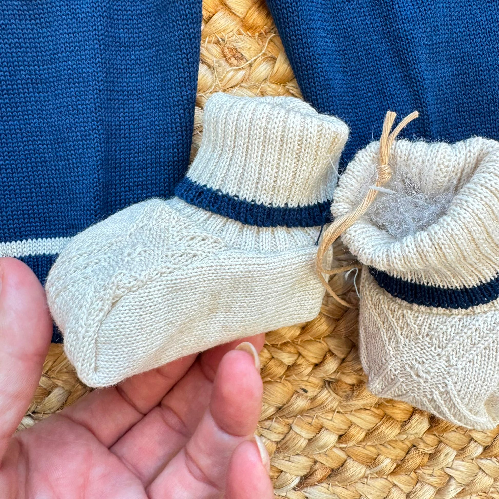 Dettaglio corredino nascita neonato con tessile bianco e orsetto ricamato beige