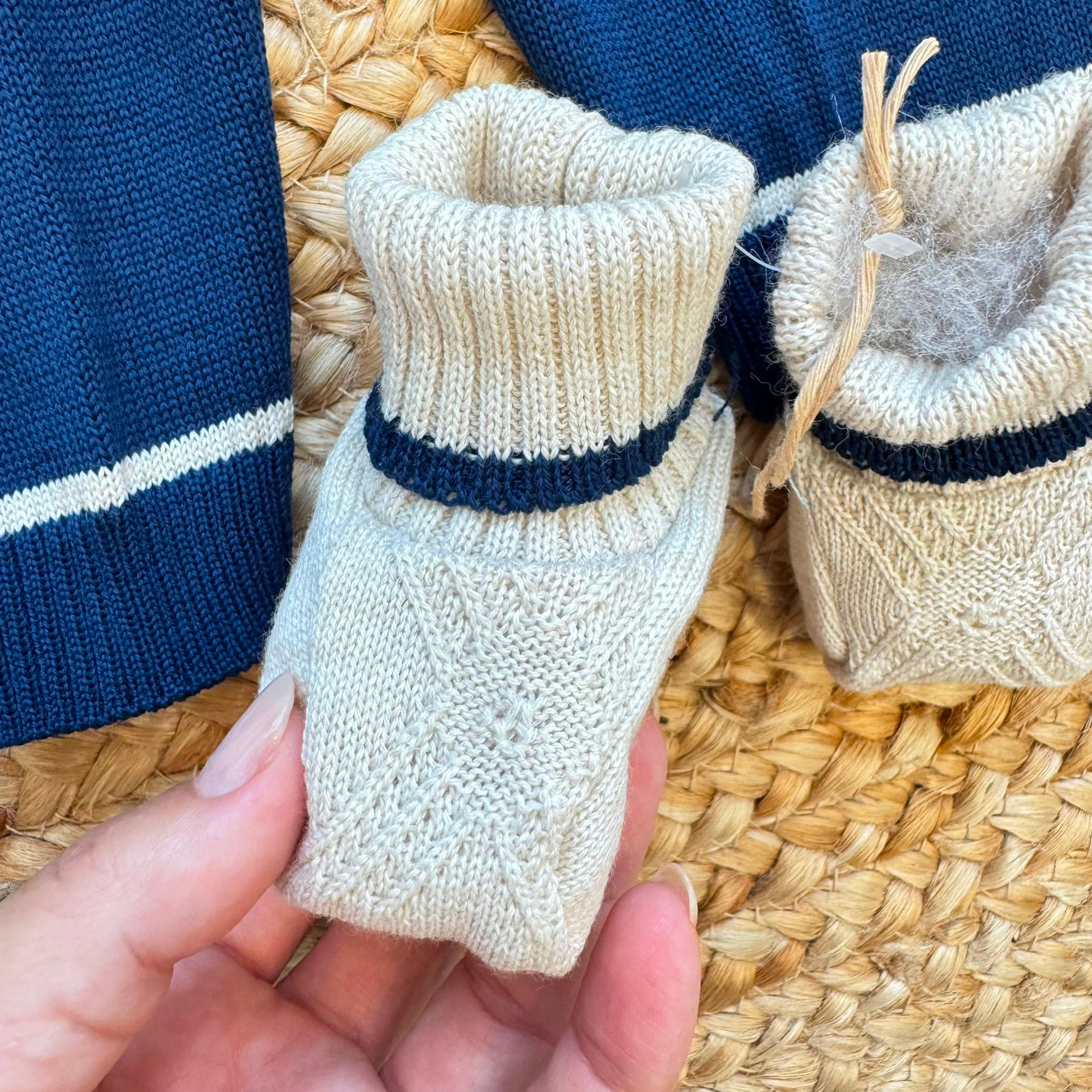 Dettaglio corredino nascita neonato con tessile bianco e orsetto ricamato beige