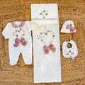 Uscita clinica neonata in ciniglia panna con ricamo floreale a cuore e fiocco rosa composta da tutina, bavetta, cappellino, lenzuola coordinate e copertina sfoderabile.