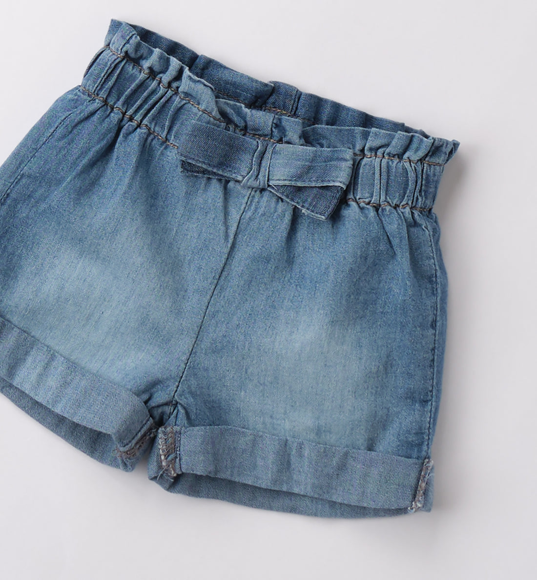 Shorts bambina in jeans con fiocco e tasche arricciate sul retro.

