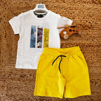 T-shirt bianca con stampa tropicale e pantaloncini gialli per bambino, abbigliamento estivo vivace.