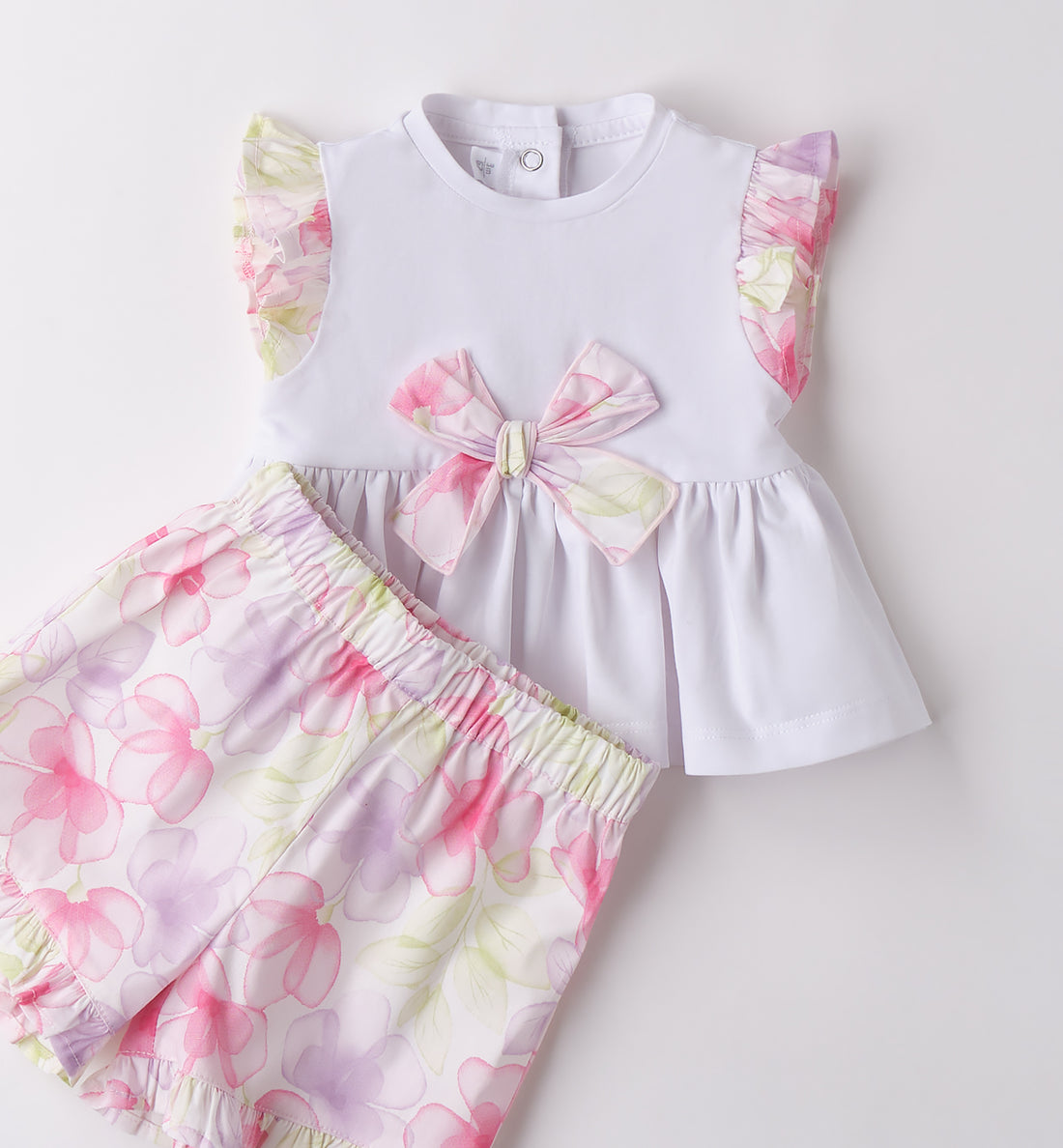 Completo bambina in cotone con top bianco e shorts floreali con balze.