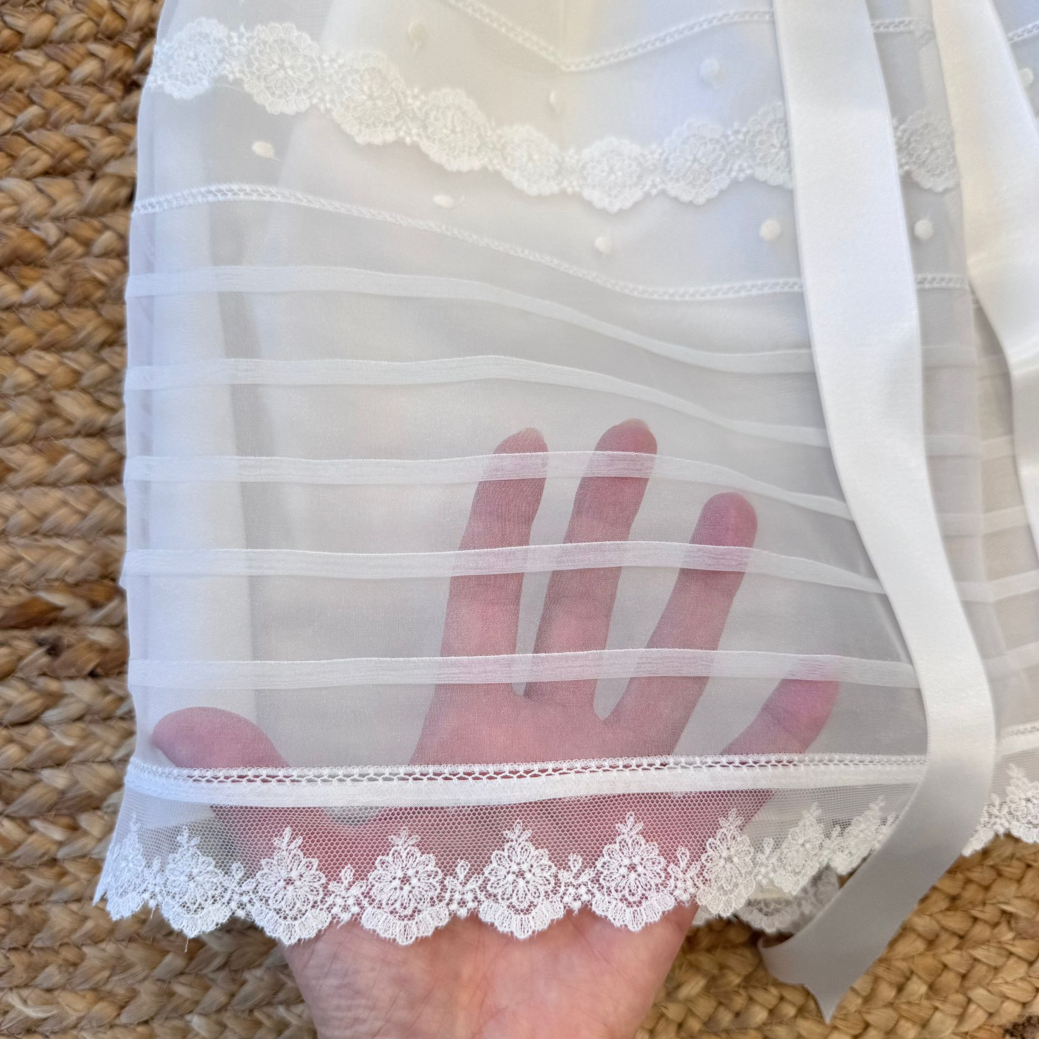 Dettaglio del bordo in tulle con ricamo floreale.