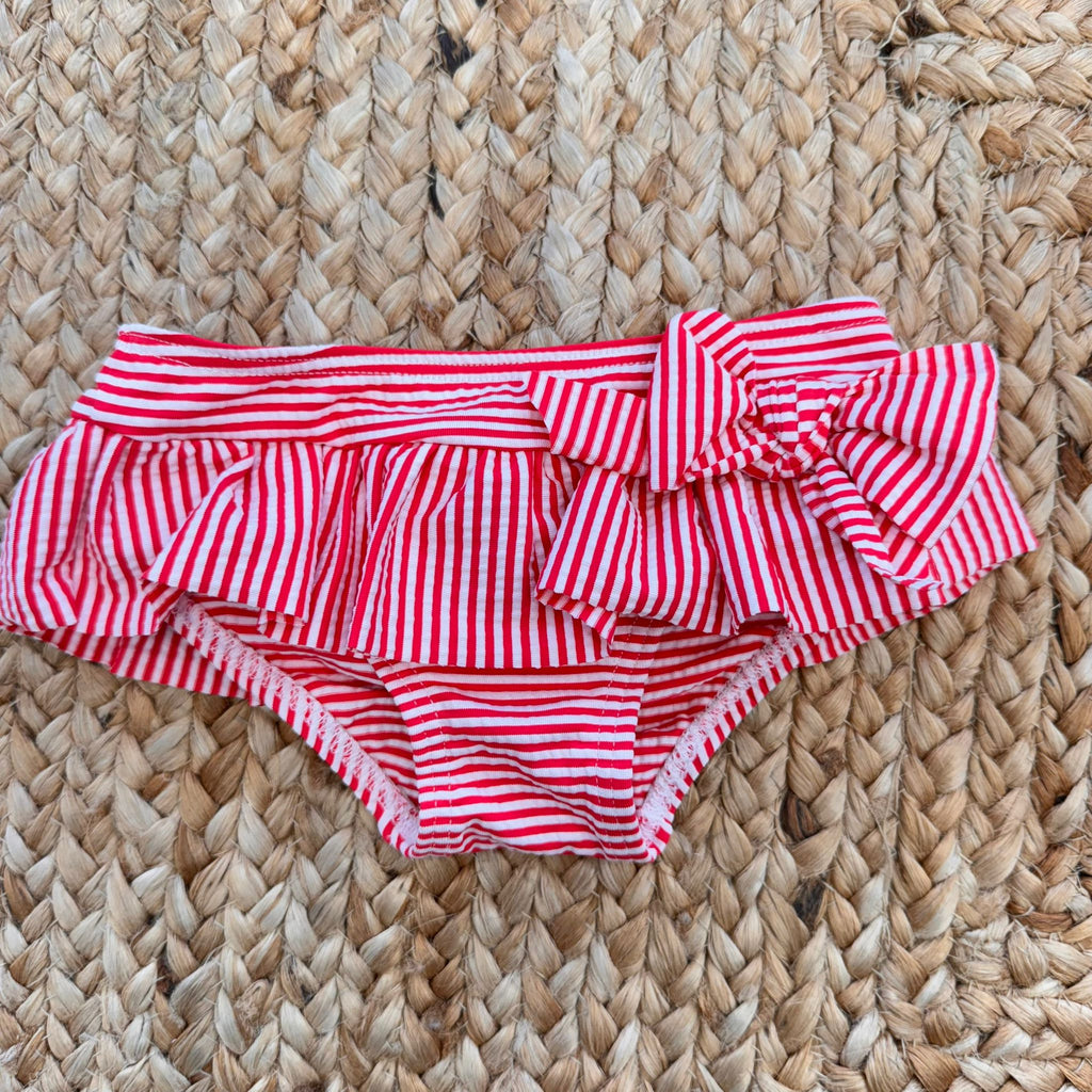 Costume slip a righe rosse con fiocco e t-shirt con stampa barchetta per bambina.

