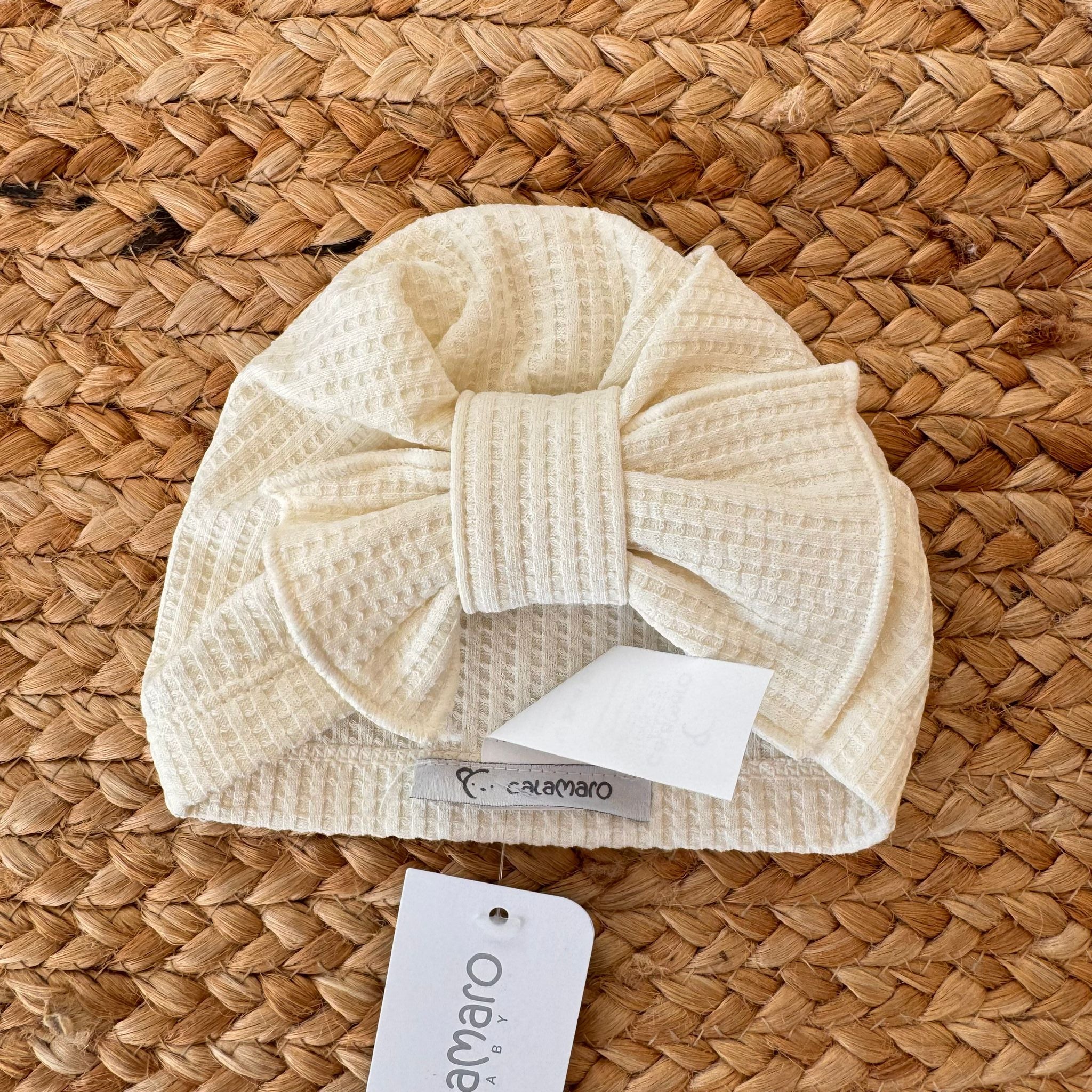 Turbante bimba color panna con fiocco in tessuto a nido d’ape.

