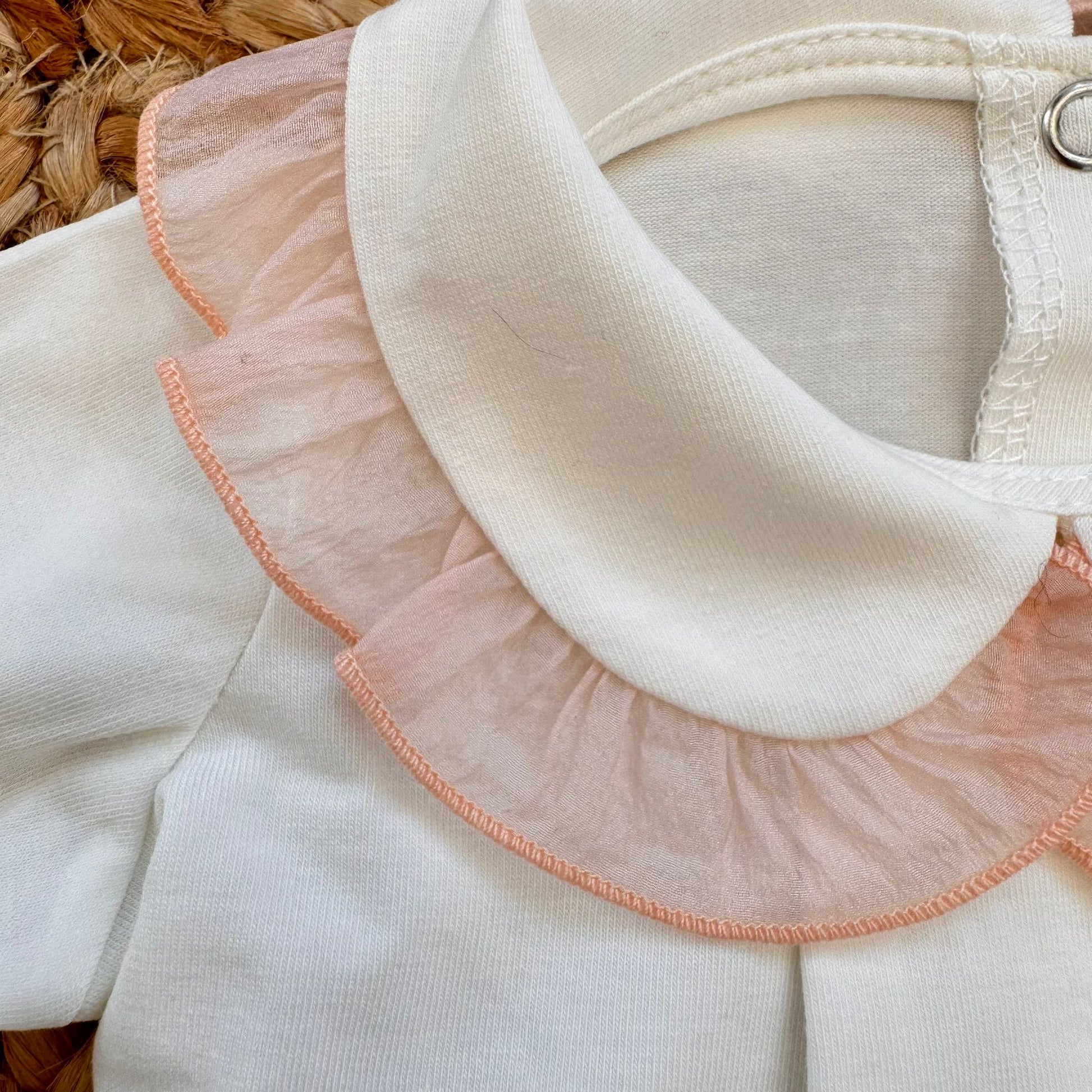 Dettaglio colletto panna con ruches rosa su tutina bimba in cotone