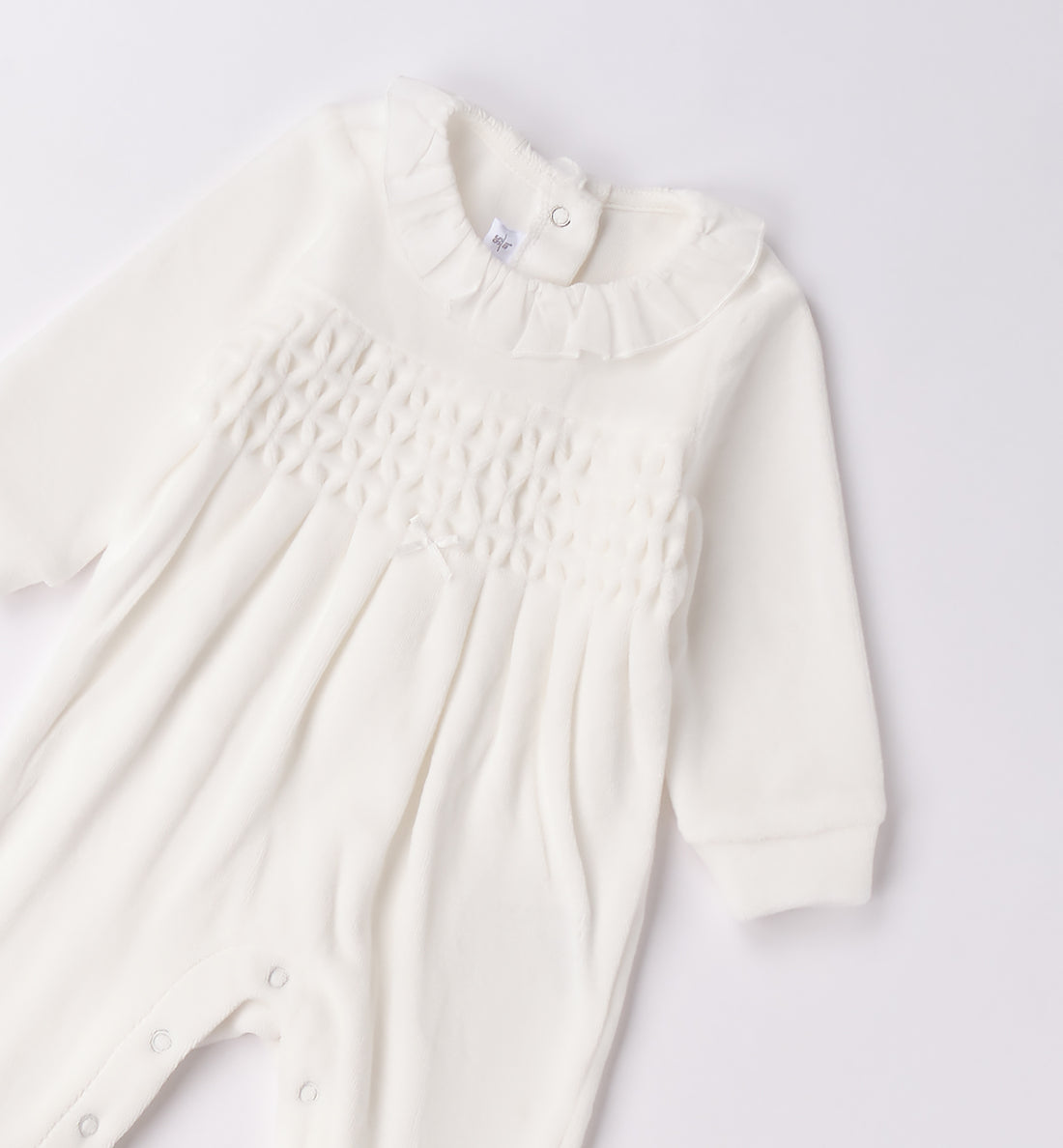 Tutina neonata in ciniglia bianco latte con ricamo nido d’ape piegata.