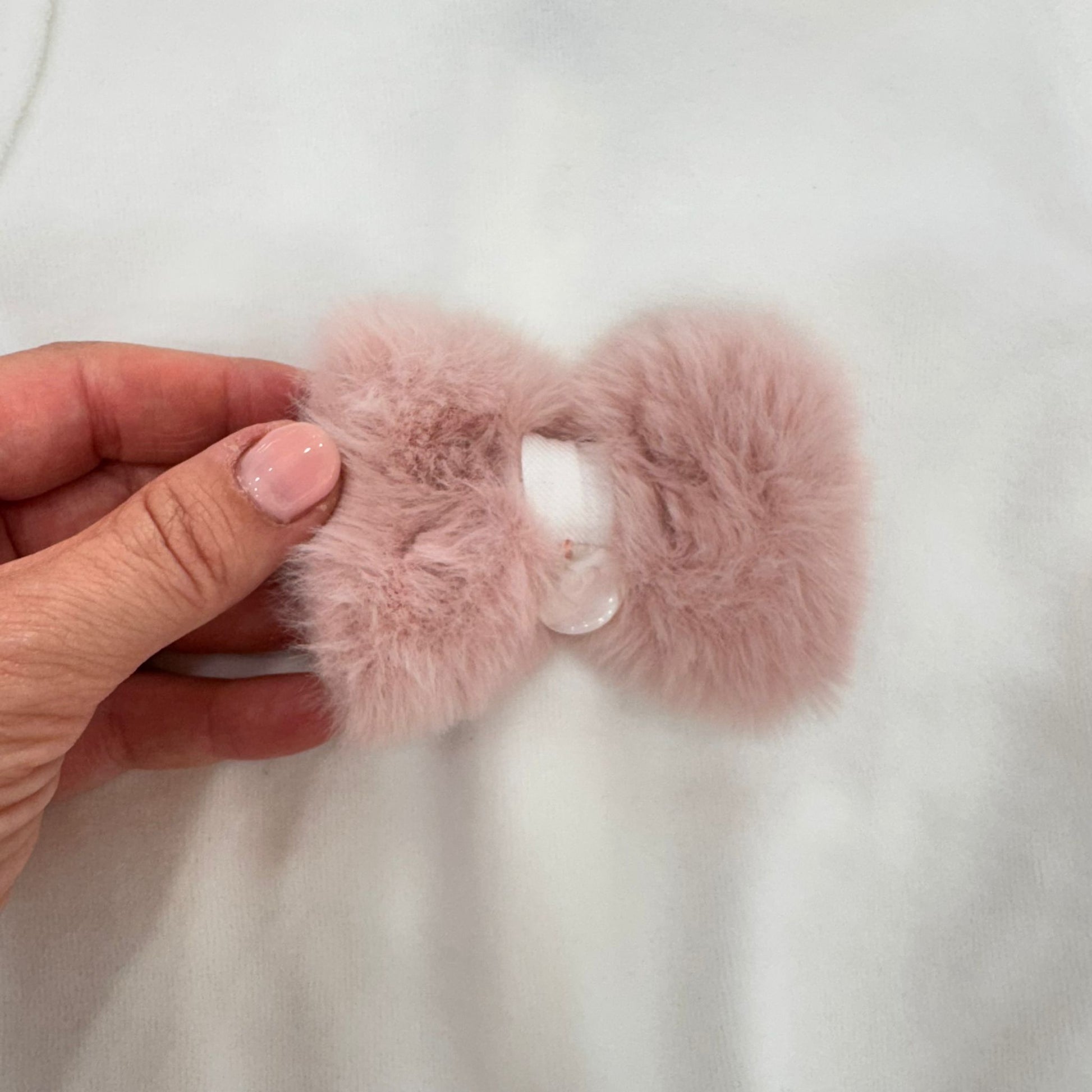 Dettaglio fiocco in pelliccia rosa sulla tutina panna in ciniglia