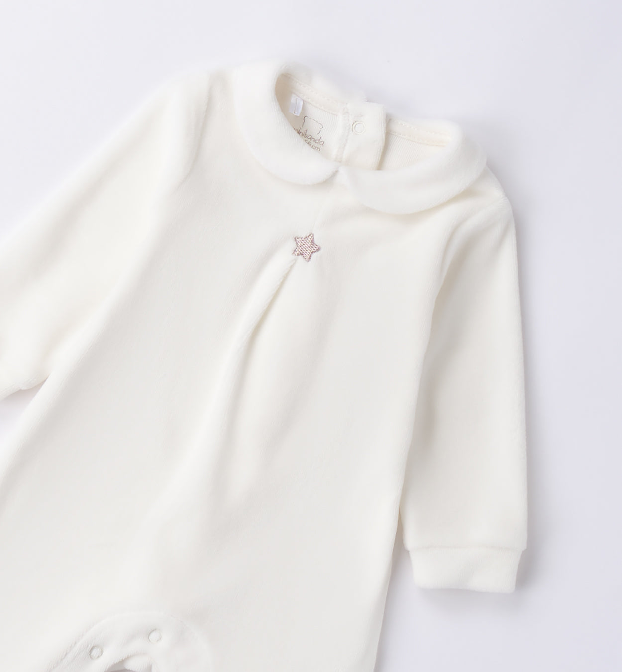Dettaglio tutina unisex in ciniglia panna con stellina beige ricamata.
