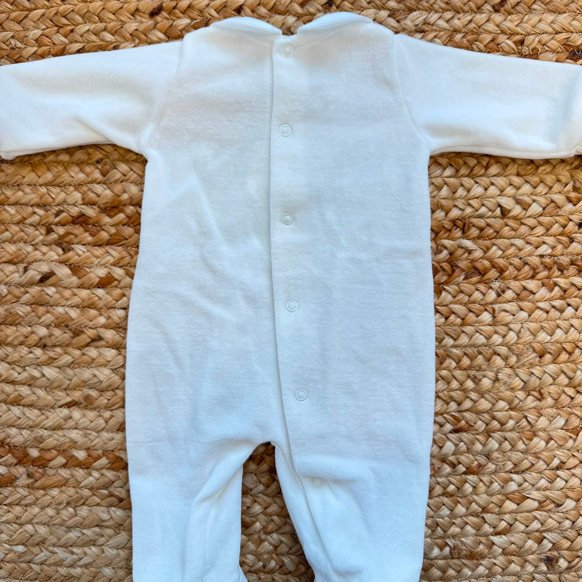 Tutina neonato in ciniglia color cielo con colletto bianco ricamato e fiocchetti.