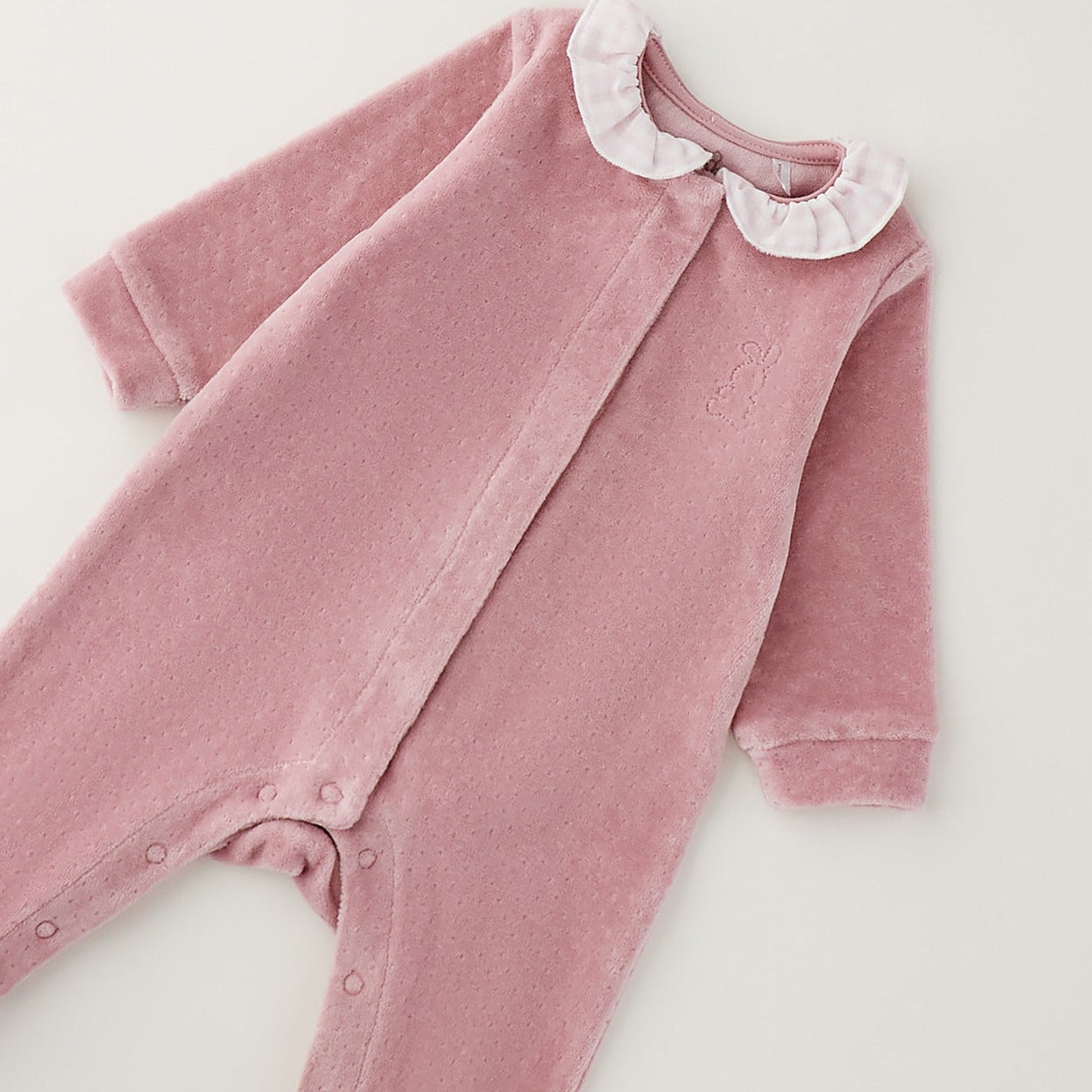 Dettaglio tutina nascita neonata in ciniglia rosa con colletto bianco a quadretti e coniglietto tono su tono.