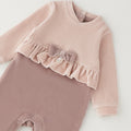 Tutina neonata in ciniglia rosa con fiocco, volant e piedini, ideale per corredino nascita bambina.