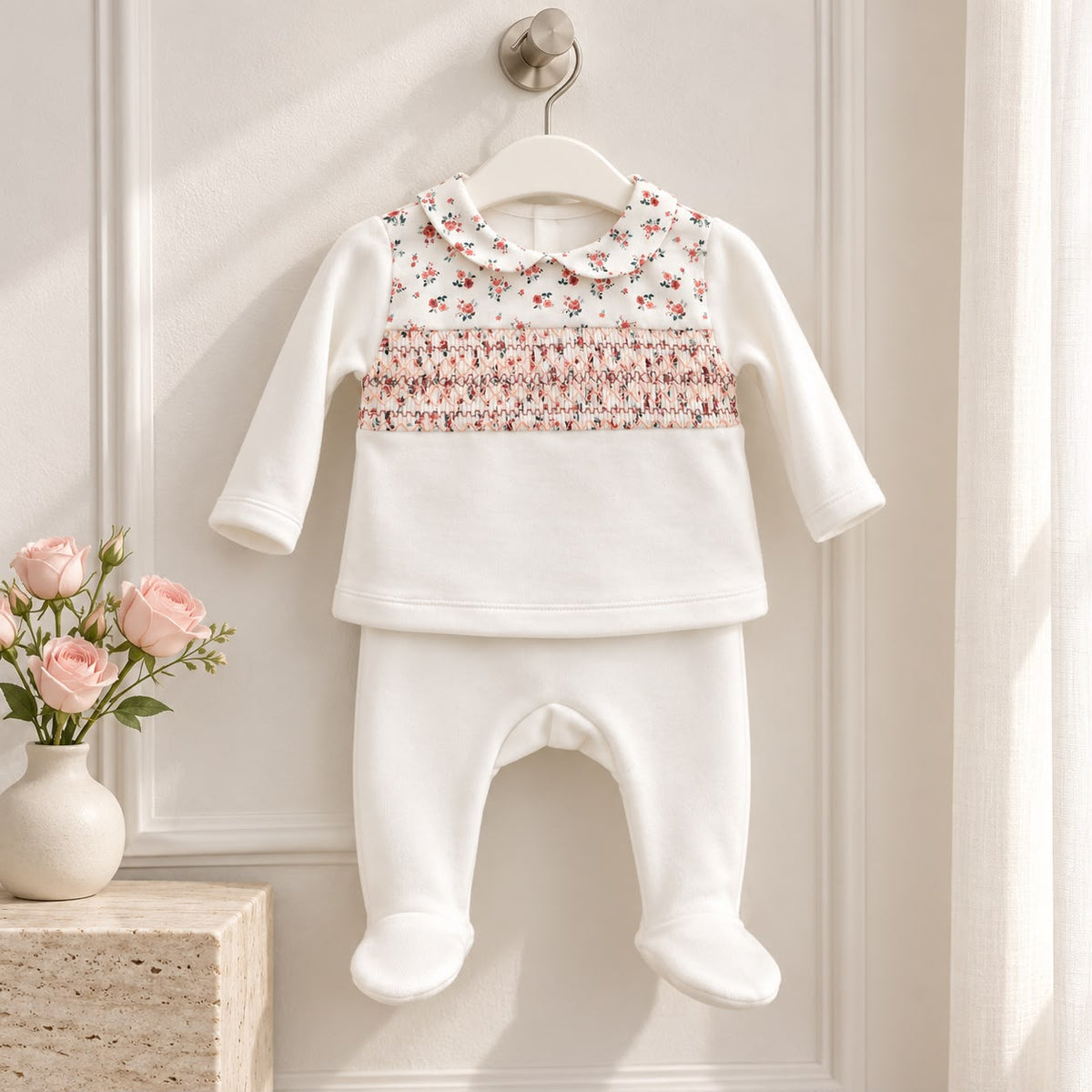 Tutina neonata in ciniglia due pezzi con punto smock, colletto floreale e ghettina con piedini. Un completo nascita romantico ed elegante.