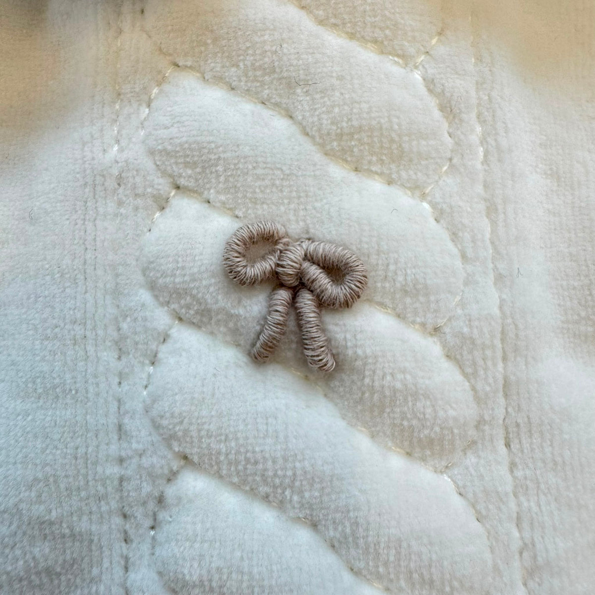 Tutina neonata in ciniglia color latte e beige con fiocchetti ricamati, ideale per corredino nascita