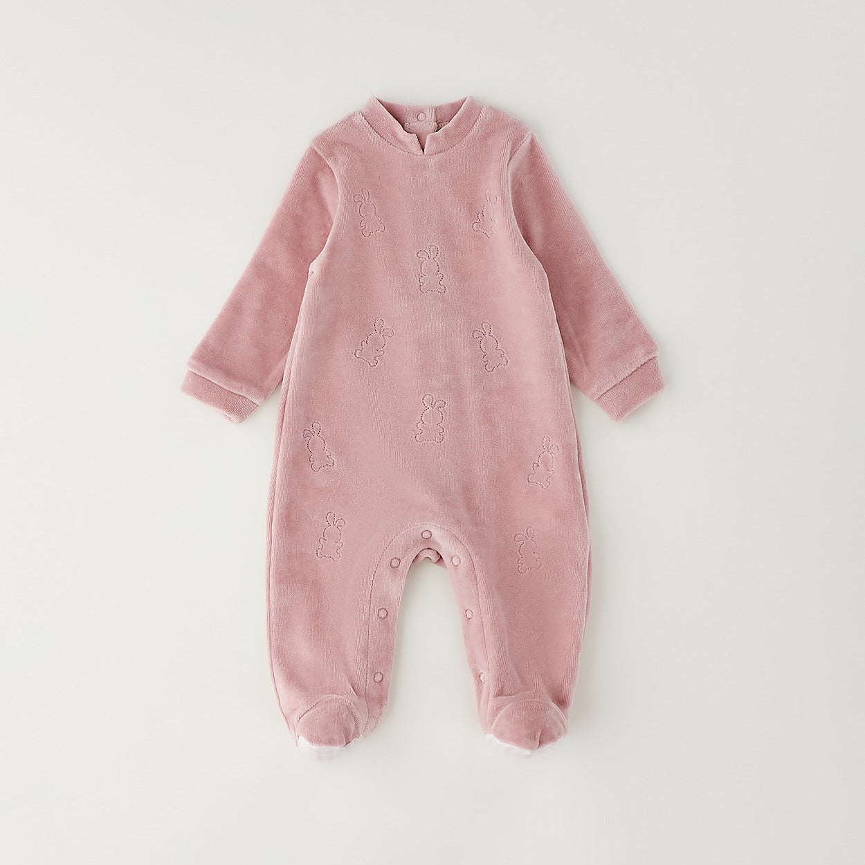 Retro tutina neonata in ciniglia rosa con chiusura a bottoncini e dettaglio a quadretti sui piedini.