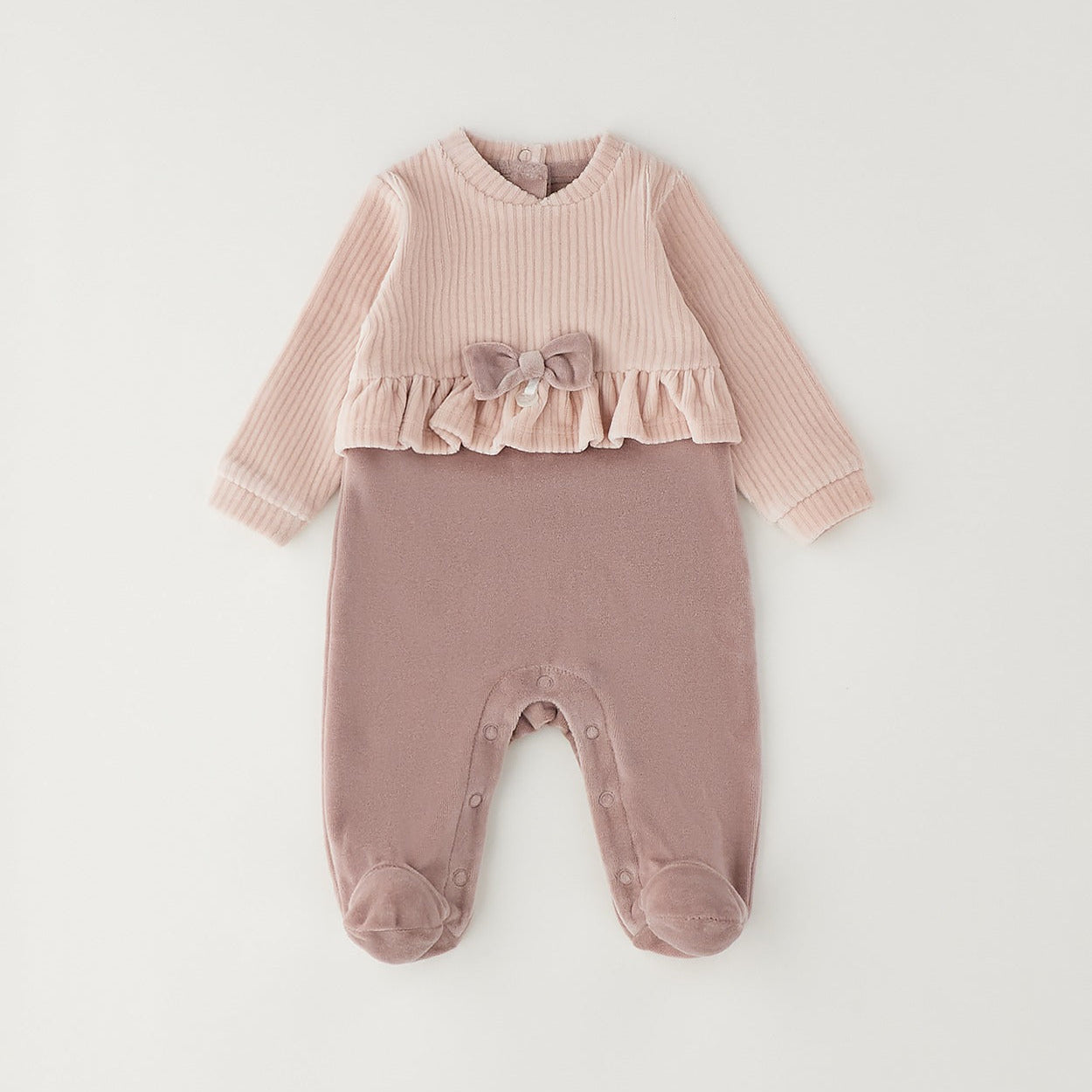 Tutina neonata in ciniglia rosa con fiocco, volant e piedini, ideale per corredino nascita bambina.