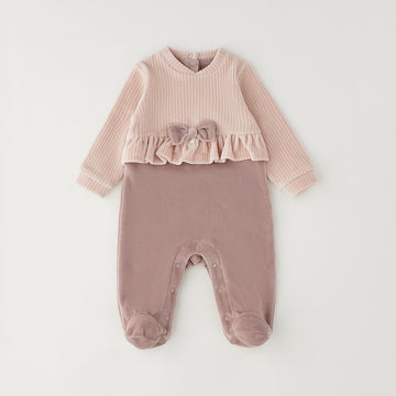 Tutina neonata in ciniglia rosa con fiocco, volant e piedini, ideale per corredino nascita bambina.