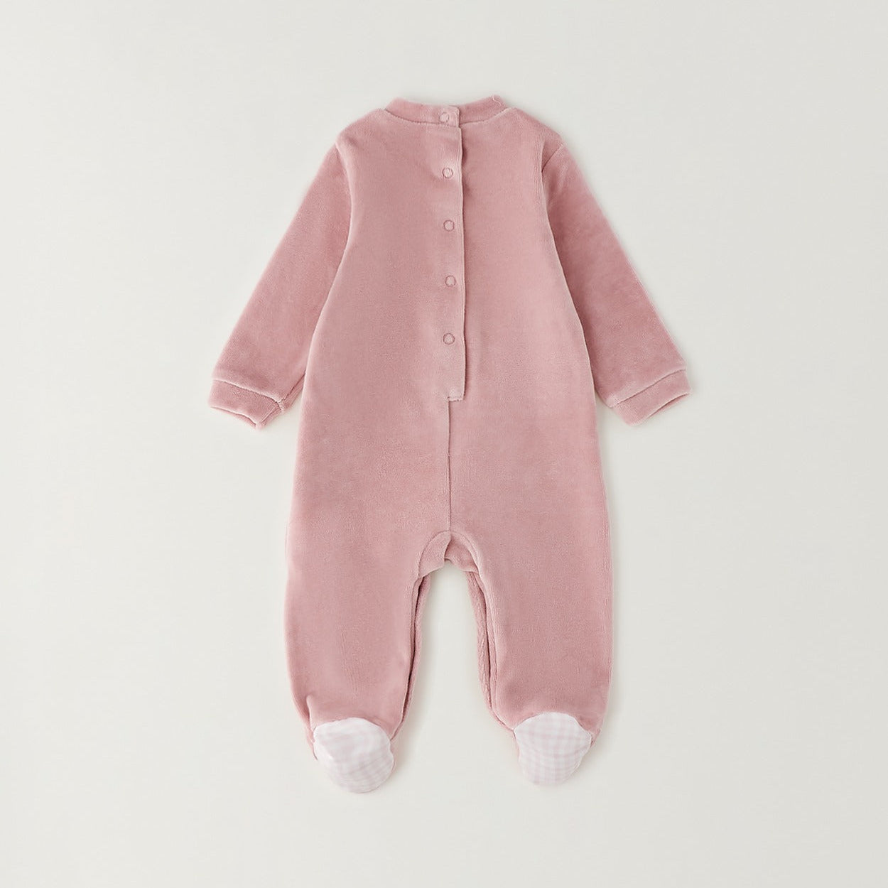 Retro tutina neonata in ciniglia rosa con chiusura a bottoncini e dettaglio a quadretti sui piedini.