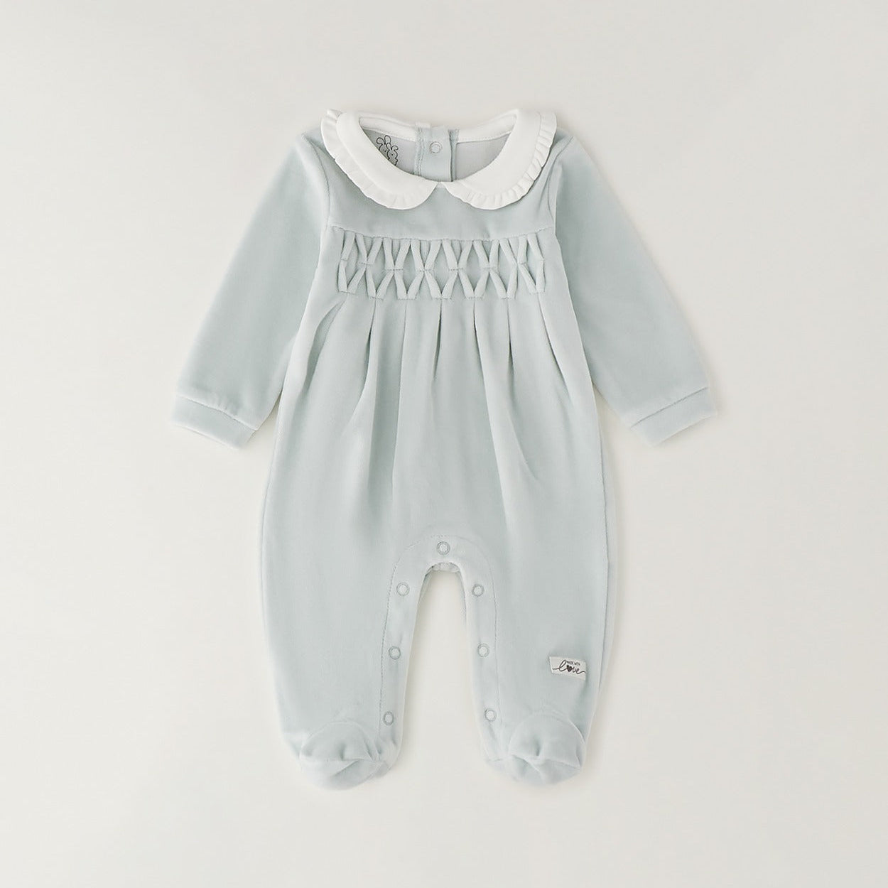 Dettaglio tutina neonata verde menta in ciniglia con colletto bianco e lavorazione smock geometrica